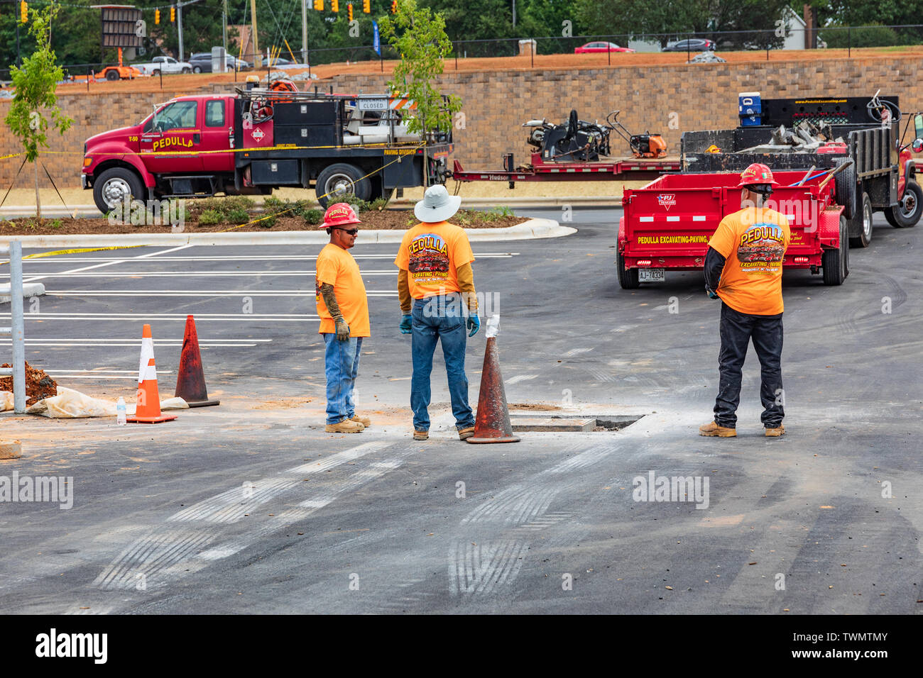 MOORESVILLE, NC, USA - Juni 19, 2019: Arbeiter warten auf Anhänger bis zu rücken, ein Ablassen in einen Parkplatz einzurichten. Stockfoto