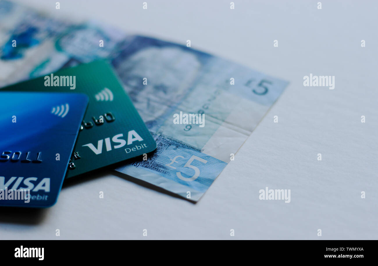 LONDON, UK, Mai 2019 zwei EC-Karten, der Barclays Bank Lloyds und 5 Pfund Note. Woman's Hand Barclays Card, Tesco Club Card im Hinterg Stockfoto