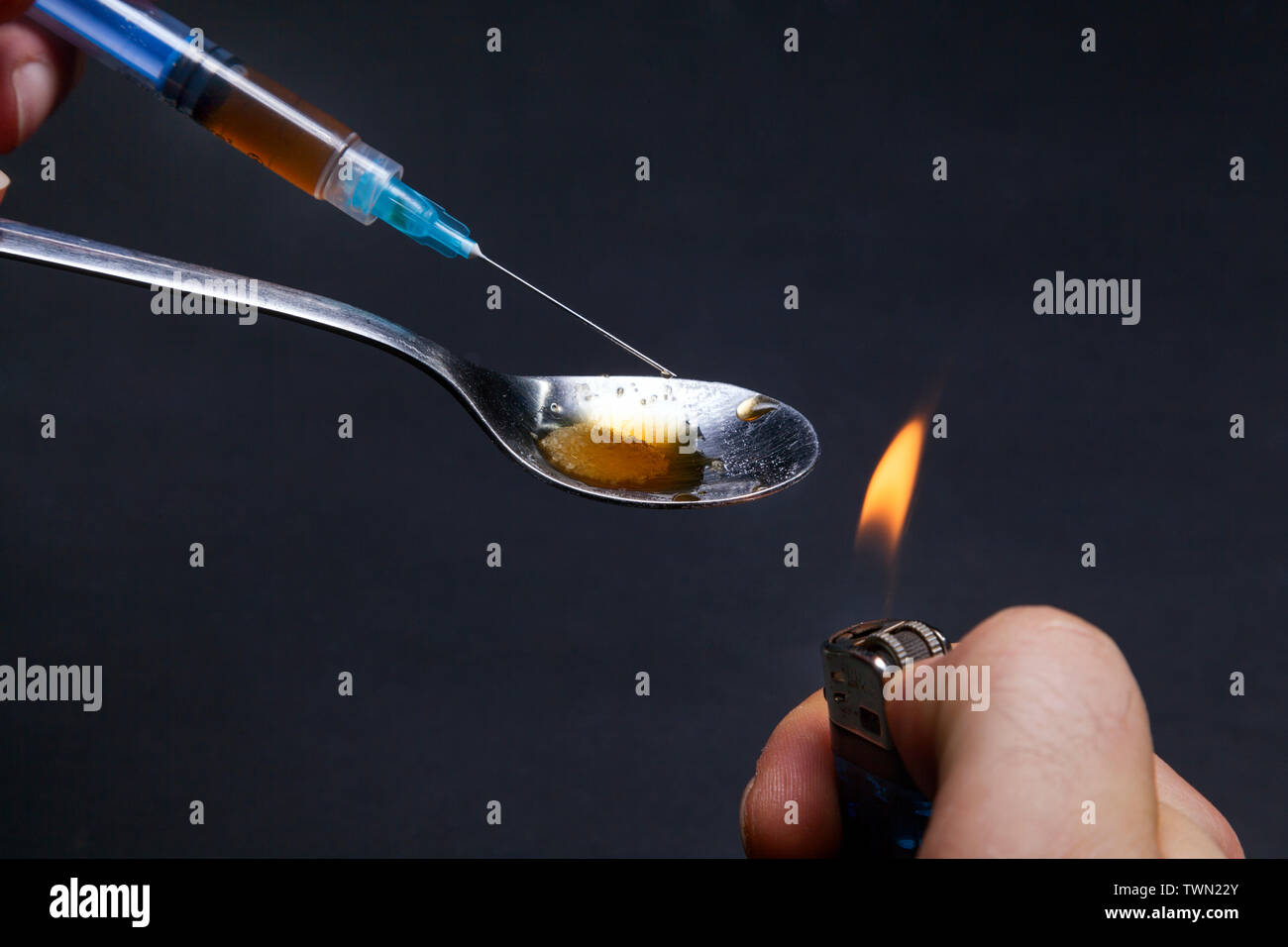 Man kocht Heroin mit einem Feuerzeug und t-Löffel. Vorbereitung seine Dosis Stockfoto