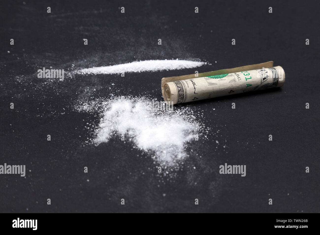 Kokainpulver in Linien und ein Dollarschein. Betäubungsstreifen, ein Haufen Drogen auf schwarzem Hintergrund. Stockfoto