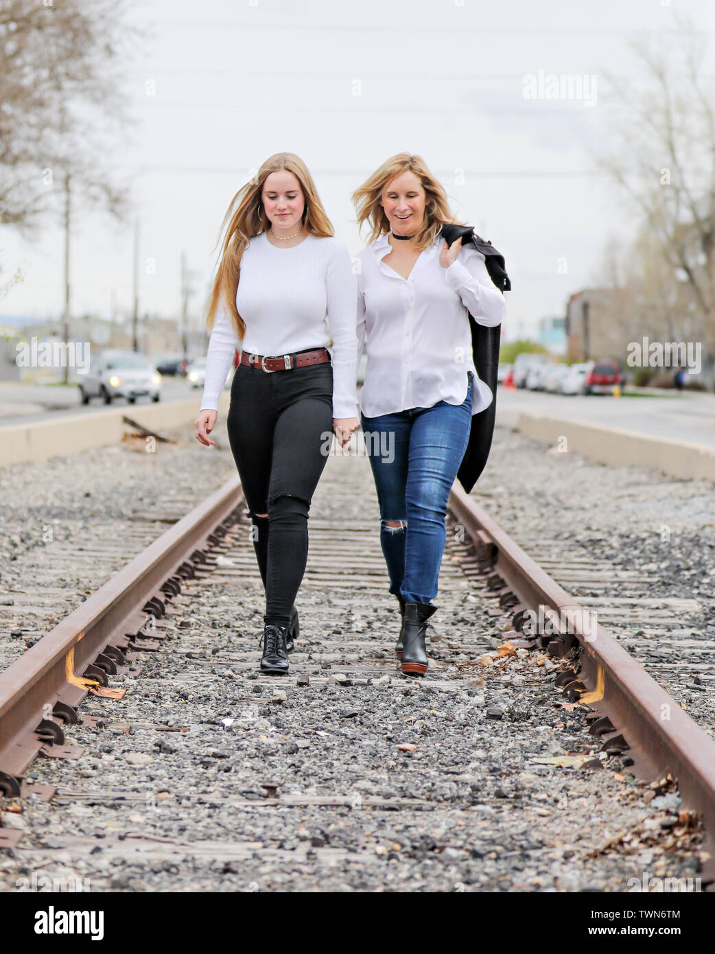 Mutter und Tochter stehen und gehen auf den Gleisen im urbanen Raum. Stockfoto