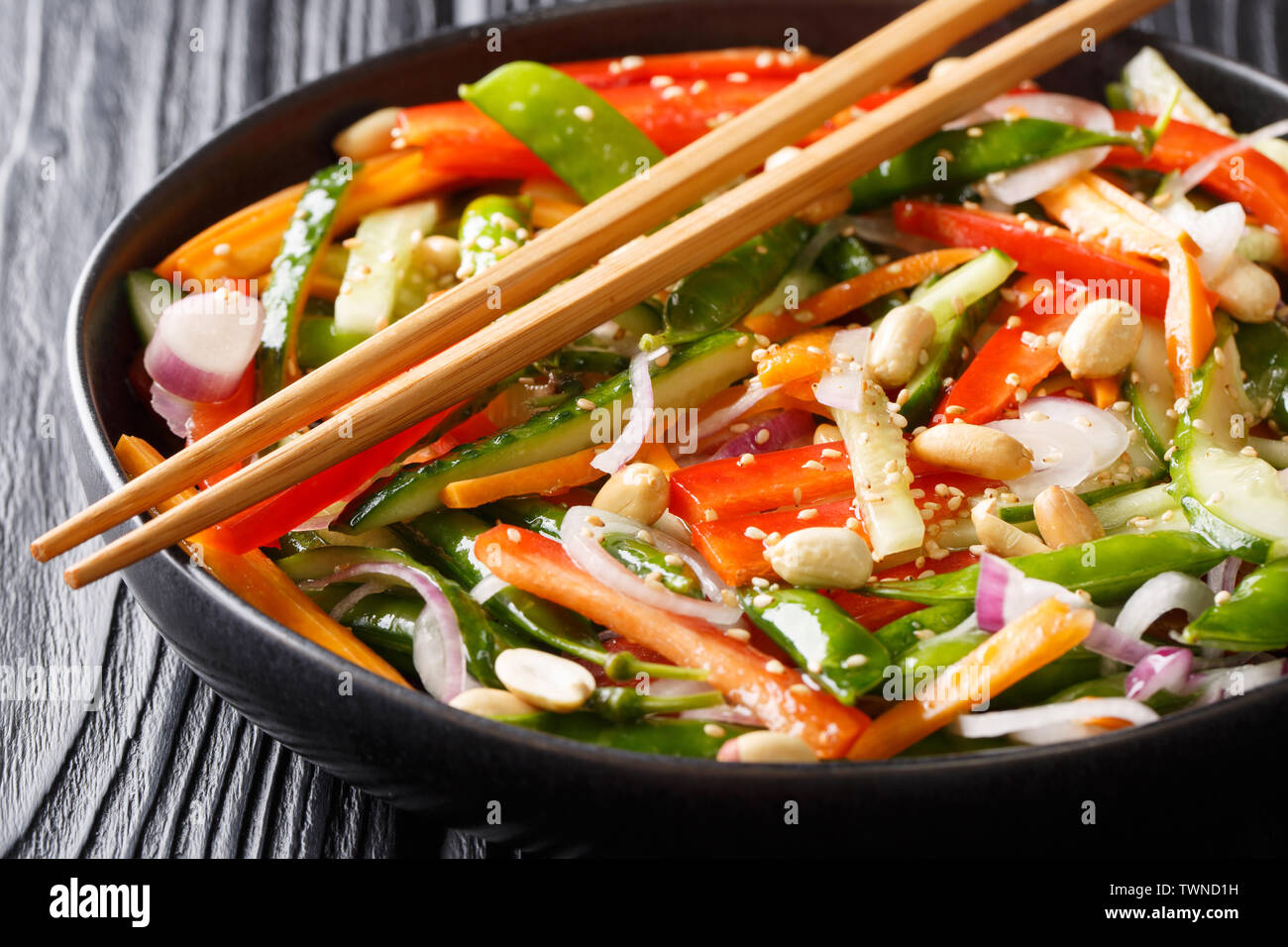 Asiatische vitamin Gemüsesalat mit Sesam und Erdnüsse close-up auf einem Teller auf den Tisch. Horizontale Stockfoto
