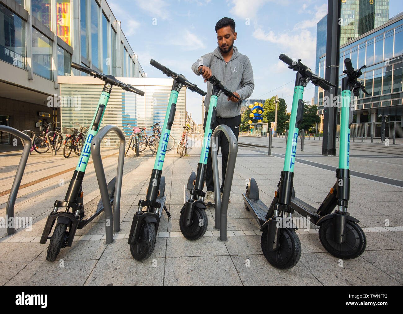 22. Juni 2019, Hessen, Frankfurt/Main: Haseeb Rafiq vom Service Provider'  Liefery" stellt einen Elektroroller am Willy-Brandt-Platz. Die Firma 'Tier  Mobilität" der e-Scooter Vermietung von Samstag beginnt. Maximal fünf  Scooter pro Parkplatz geplant,