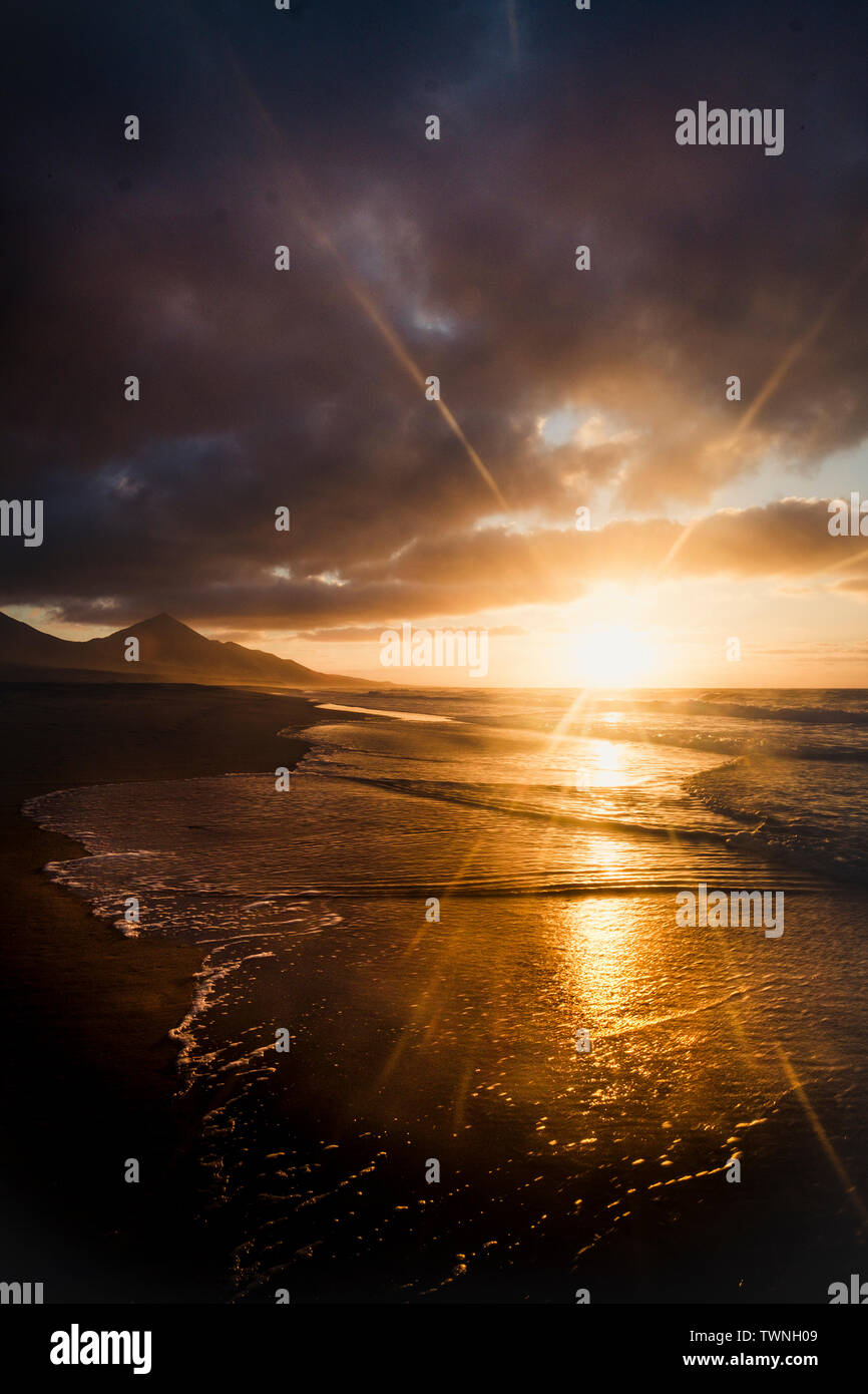 Dunkle schöne Natur Sonnenuntergang mit Wellen im Meer und Berge im Hintergrund - Sonnenlicht Wirkung und wilde Schönheit der Natur im malerischen Ort für Stockfoto