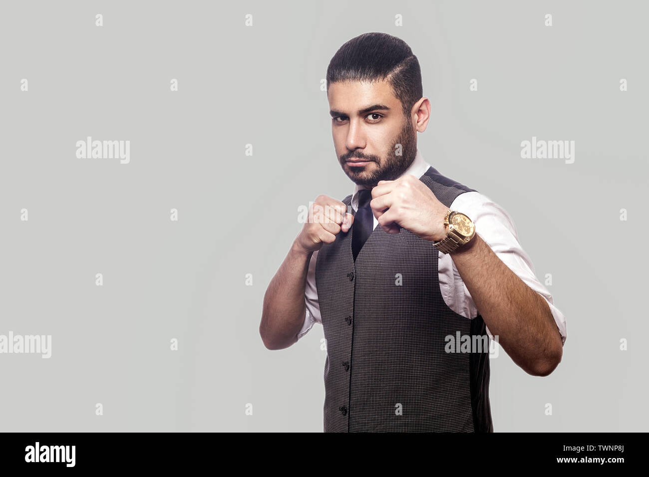 Porträt von Ernst bärtiger Mann im weißen Hemd und Weste mit Boxing Fäuste und Kamera mit aggressiven Gesicht und zum Angriff bereit Stockfoto