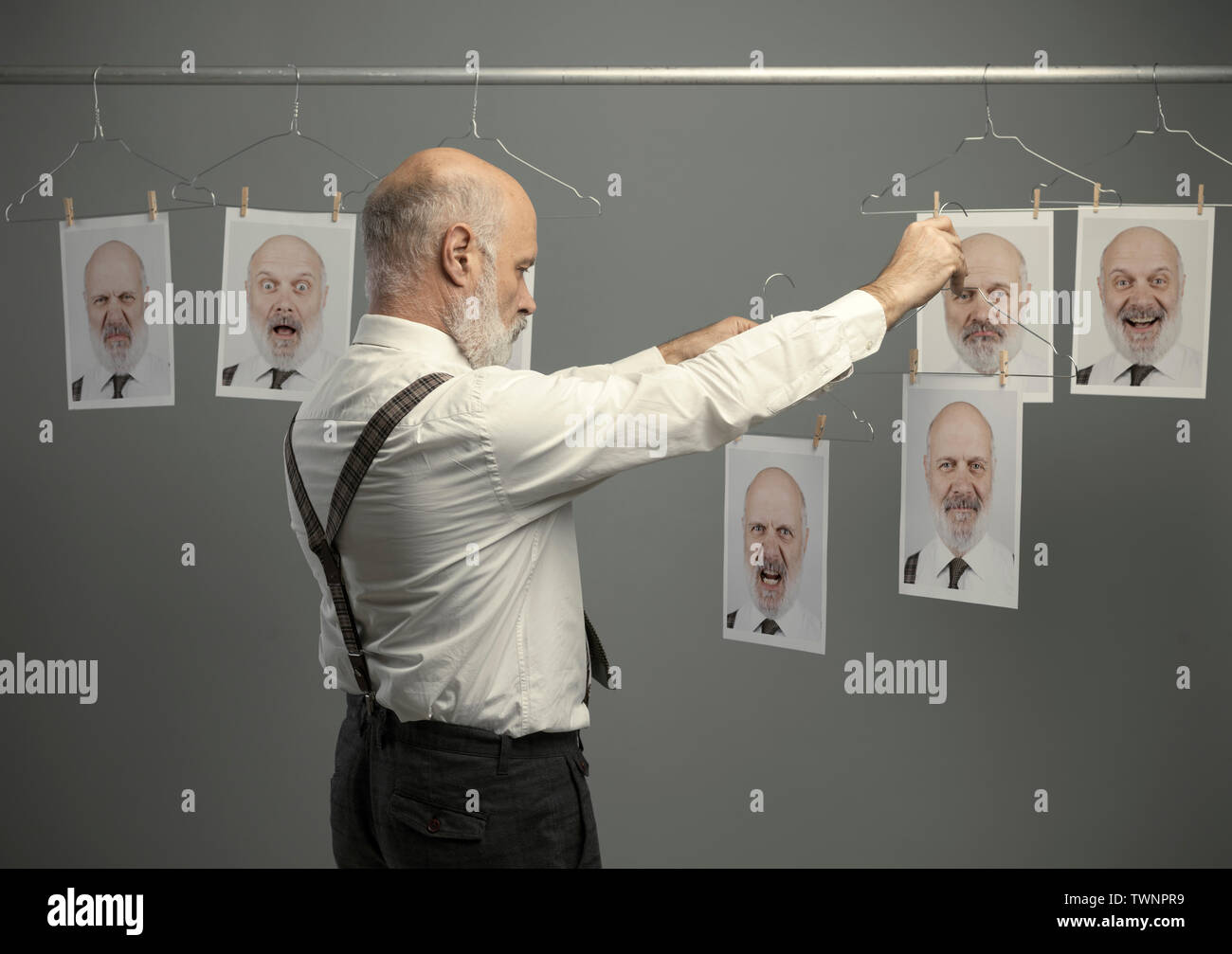 Reifen Geschäftsmann auf seine unterschiedlichen Persönlichkeiten starrte auf eine Sammlung von hängenden Porträts und einen Vergleich: verstand Selbstanalyse und Emotion Stockfoto