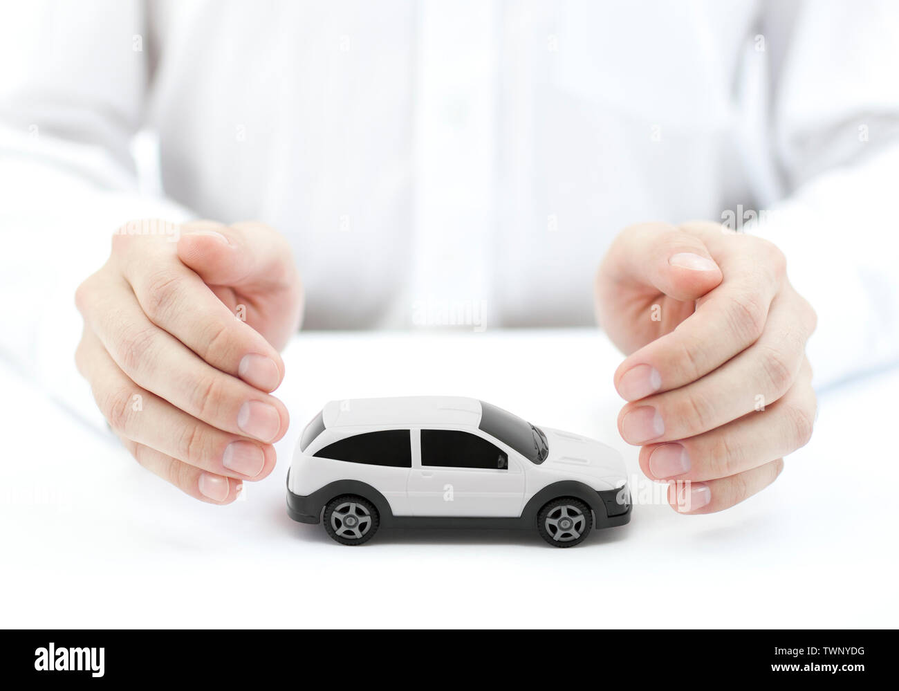 Auto Versicherung Konzept mit weißen Auto Spielzeug von Händen bedeckt Stockfoto