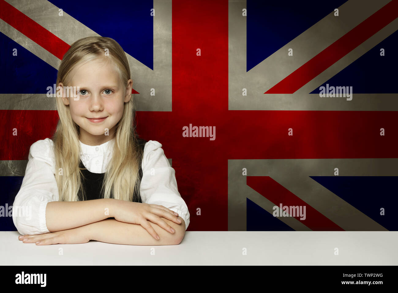 Glückliches Kind Schüler im Klassenzimmer gegen die britische Flagge Hintergrund sitzen. Lernen Sie Englisch Sprache Konzept Stockfoto