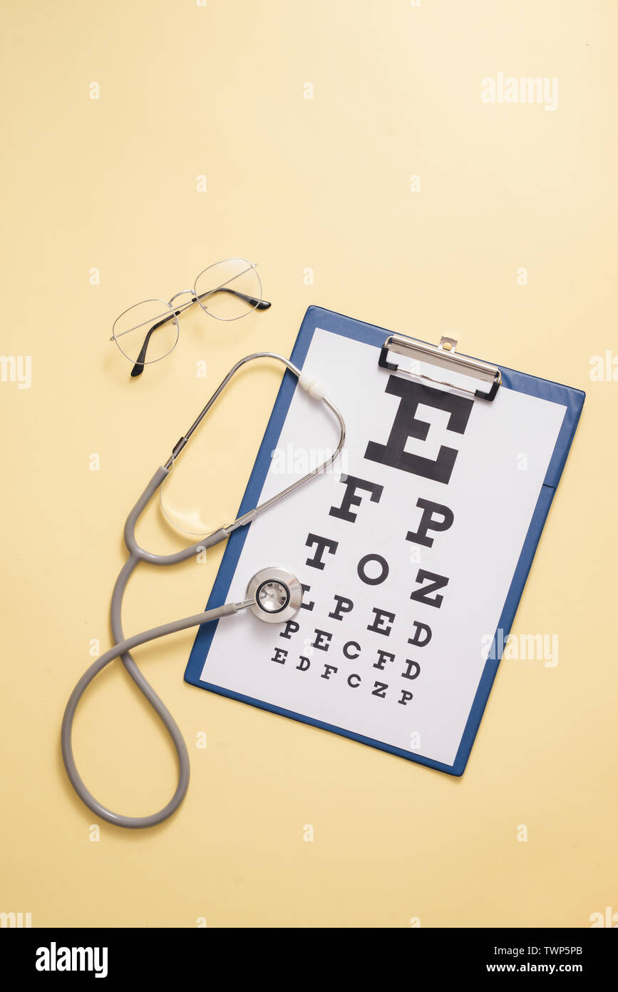 Tabelle für visual acuity Test und medizinische Stethoskop ist in gelben Hintergrund. Konzept der Auge Diagnose, Nachweis von Augenkrankheiten in der Ophthalmologie Stockfoto