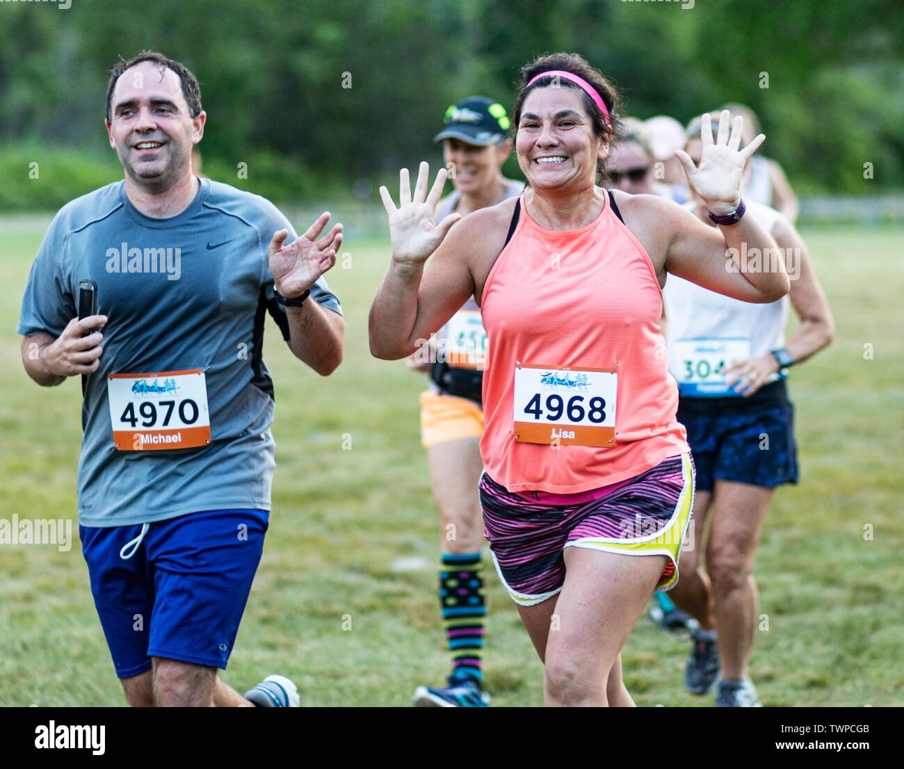 Kings Park, New York, USA - 17. Juni 2019: Aufgeregt Läufer winkt in die Kamera während der New York State Parks Sommer Serie 10 K laufen An Wanne Wiese. Stockfoto