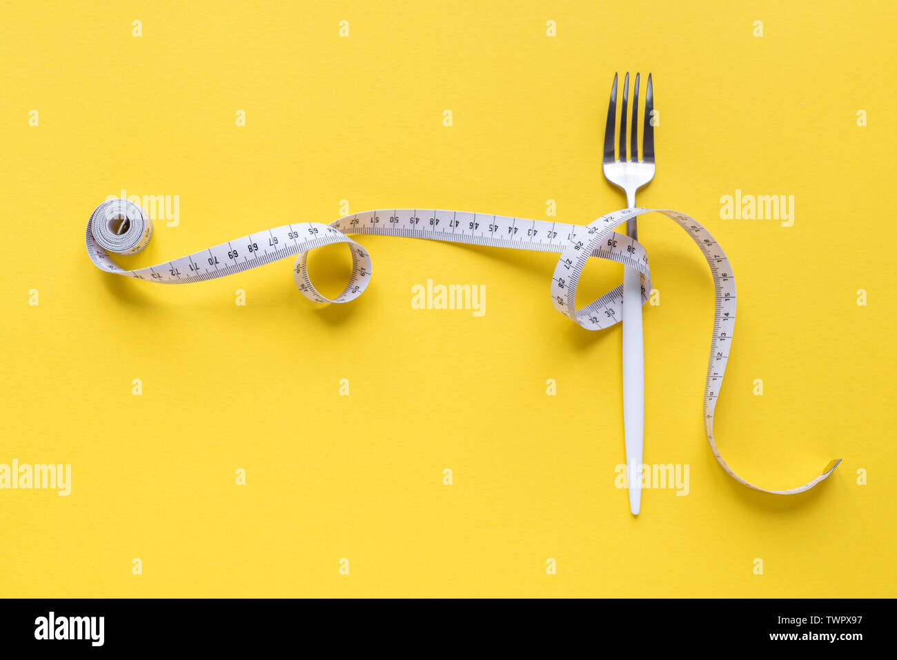 Gabel und Maßband auf gelbem Hintergrund, kopieren. Ernährung, gesunder Lebensstil, Gewichtsverlust Konzept mit weißen Gabel und Maßband. Stockfoto