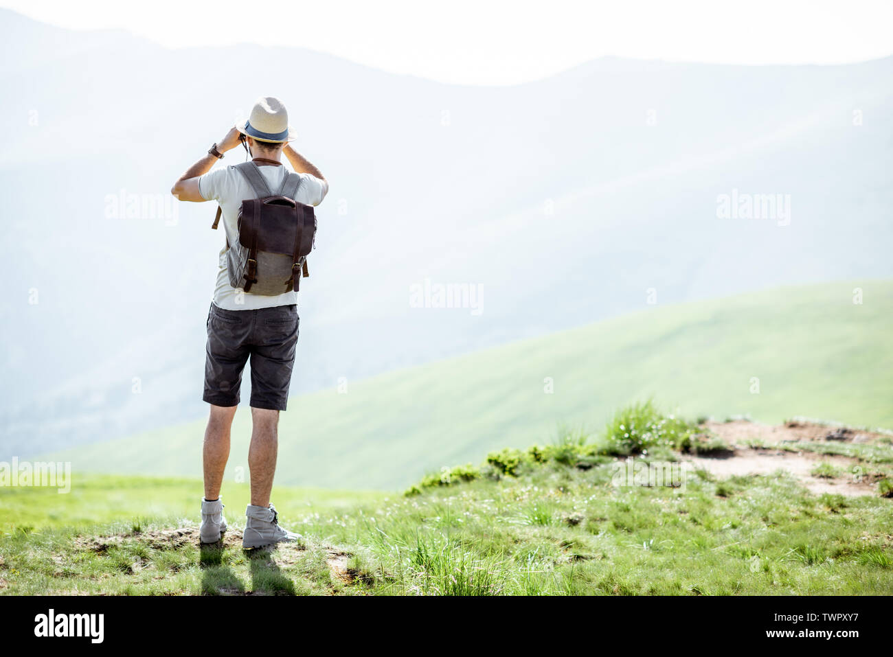 Man geniesst die herrliche Aussicht auf die Berge, Blick auf das Fernglas  unterwegs mit Rucksack in den Bergen während der sonnigen Wetter  Stockfotografie - Alamy