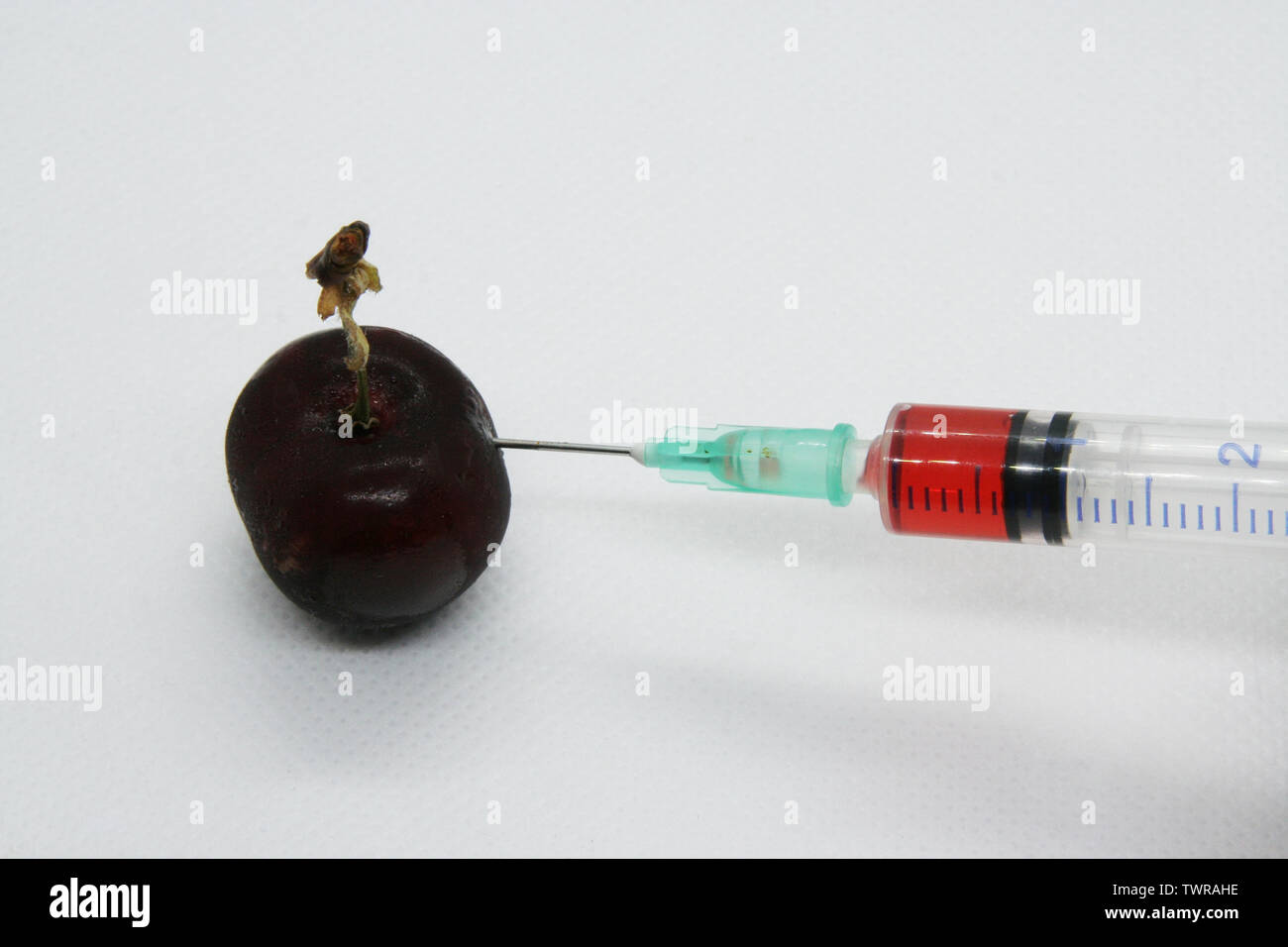 Cherry und ein Medikament in einer Spritze. Essen Schutz. Genetisch veränderter Organismus. Stockfoto