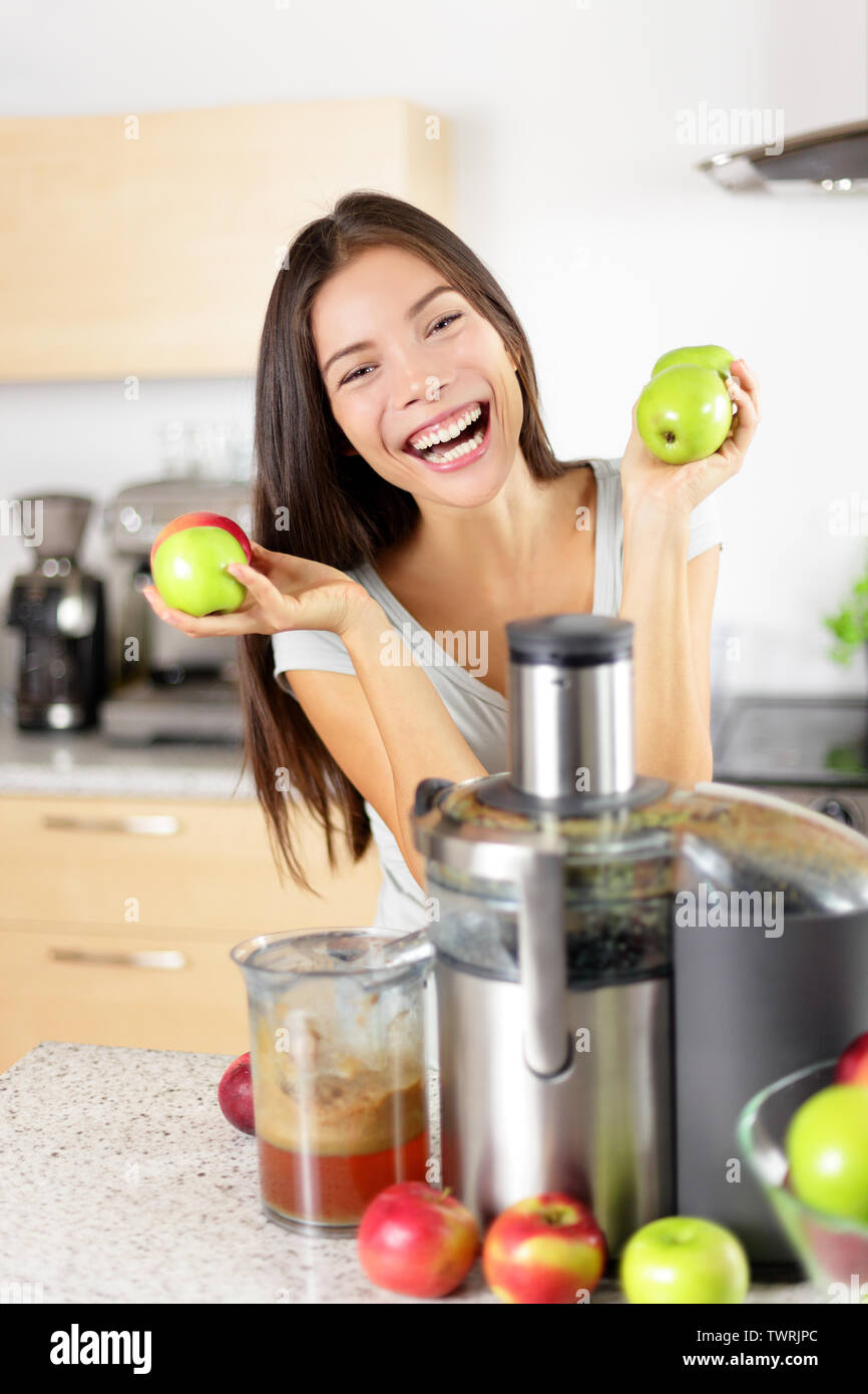 Apfelsaft - Frau, Apfelsaft auf entsafter Maschine zu Hause in der Küche. Entsaften und gesundes Essen glücklich Frau, grünes Gemüse und Obst Saft. Gemischte Rasse asiatischen Kaukasischen Modell. Stockfoto