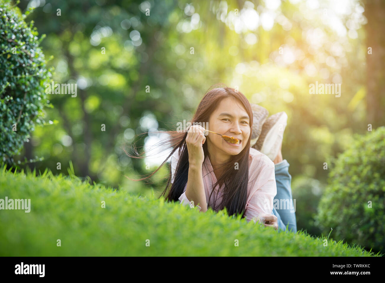 Entspannt junge schöne Frau mit lächelnden Gesicht im Park. Zeit zum Entspannen nach der Arbeit. Horizontale. verschwommenen Hintergrund. Film Effekt. Stockfoto