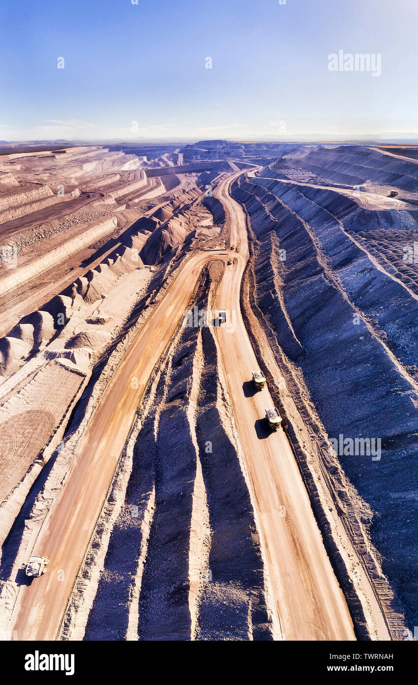 Tief aufgeschnitten Black Coal Mine von Thorley mount in Hunter Valley, Australien. Vertikal von Oben nach Unten Blick auf riesigen Trucks moving raw Mineralien. Stockfoto