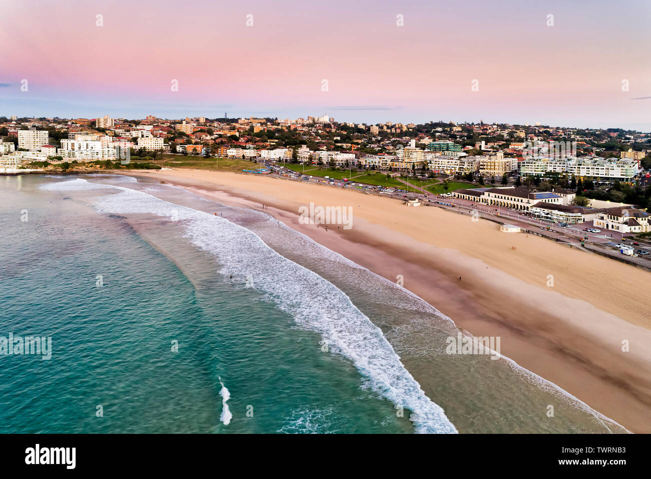 Sanften ruhigen Wellen des Pazifischen Ozeans an Land rollen von Bondi Beach mit Surfer Reiten die Wellen in der frühen Stunde vor Sonnenaufgang. Entspannende Sydney australische Leben Stockfoto