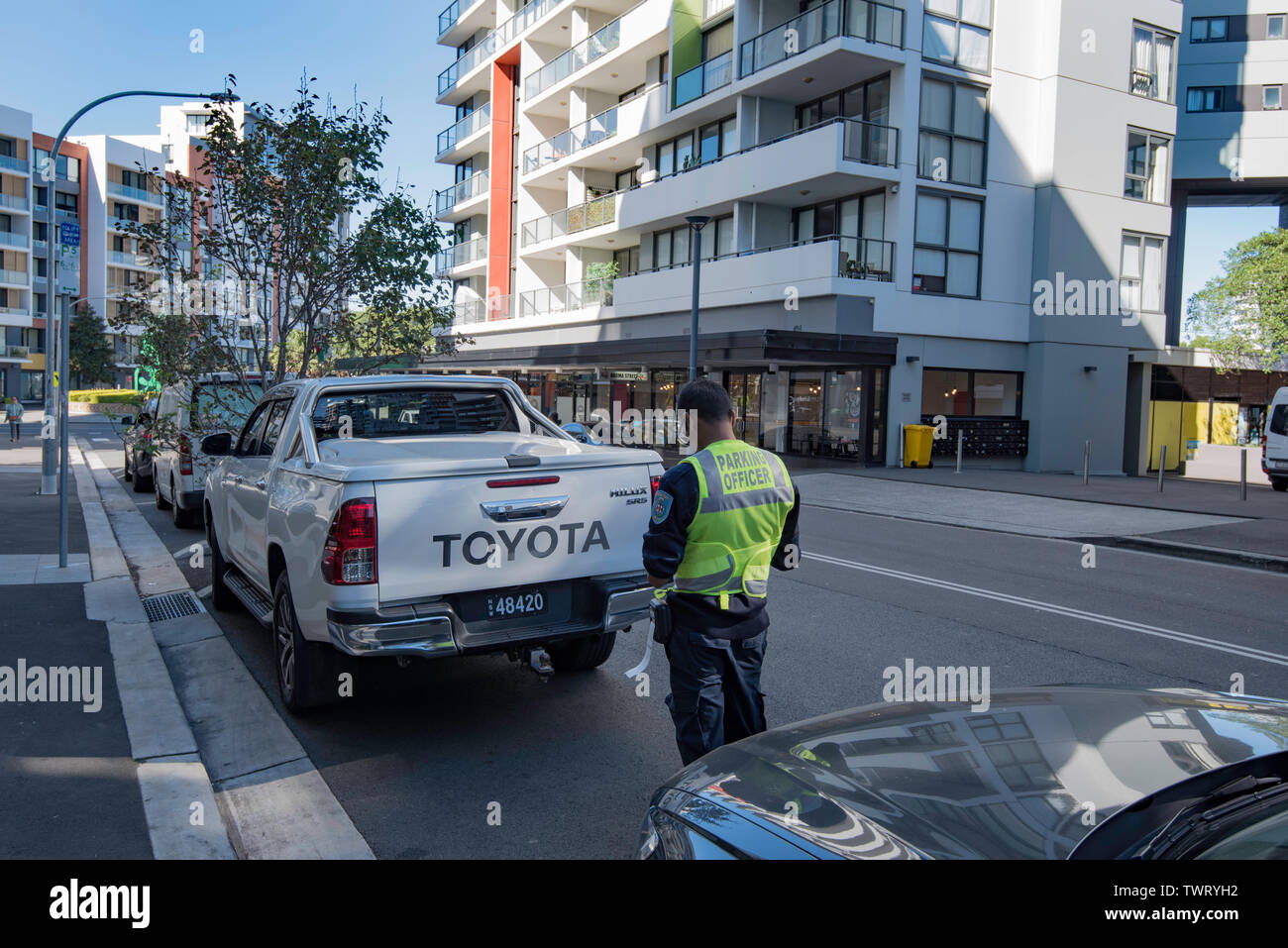 Ein Parkplatz Patrol Officer schreibt eine Verletzung Hinweis für einen illegal geparkten Fahrzeug in die Innenstadt von Sydney Vorort von Wolli Creek, Australien Stockfoto