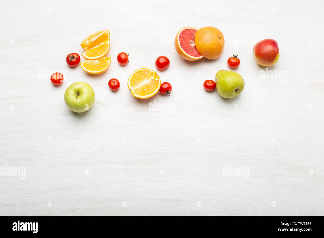 Verschiedene Obst orange Scheiben in Birnen und Äpfel liegen in der Nähe von roten Tomaten auf einem weißen Tisch mit kopieren. Veganes essen Konzept. Werbeflächen Stockfoto