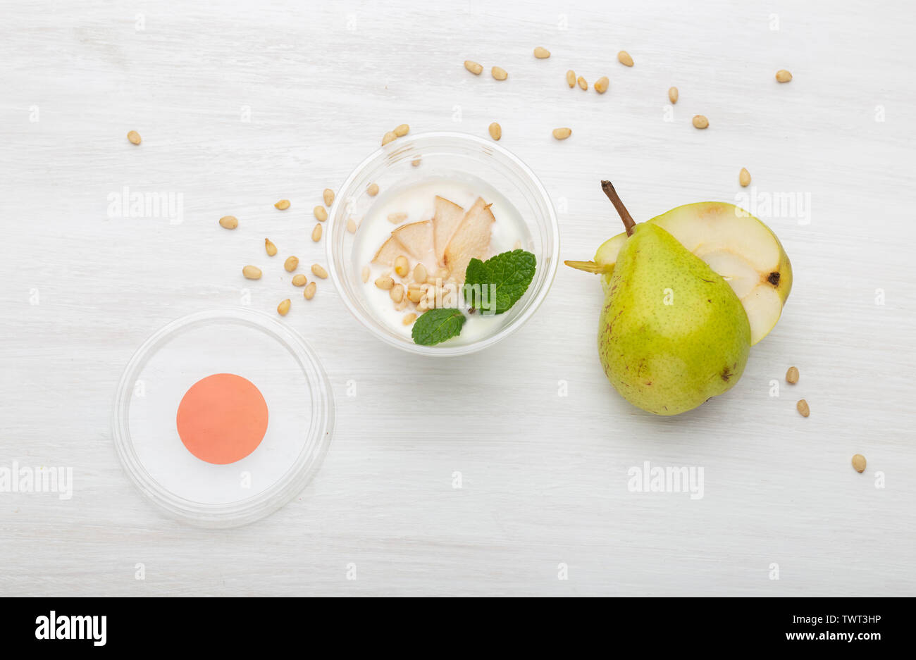 Joghurt birne Schichten und Minze und Pinienkernen liegen in einem Lunch Box auf einem weißen Tisch mit Pinienkernen und Birne Schichten, zerstreut werden. Gesunde Ernährung Konzept Stockfoto