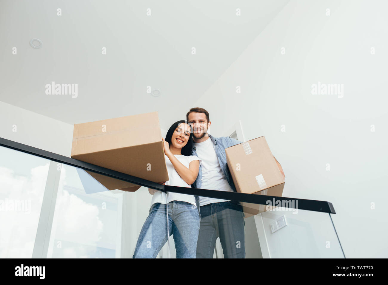 Junge schöne Paar in eine neue Wohnung. Schöne Frau und Mann mit Kartons in neuen Wohnungen Stockfoto