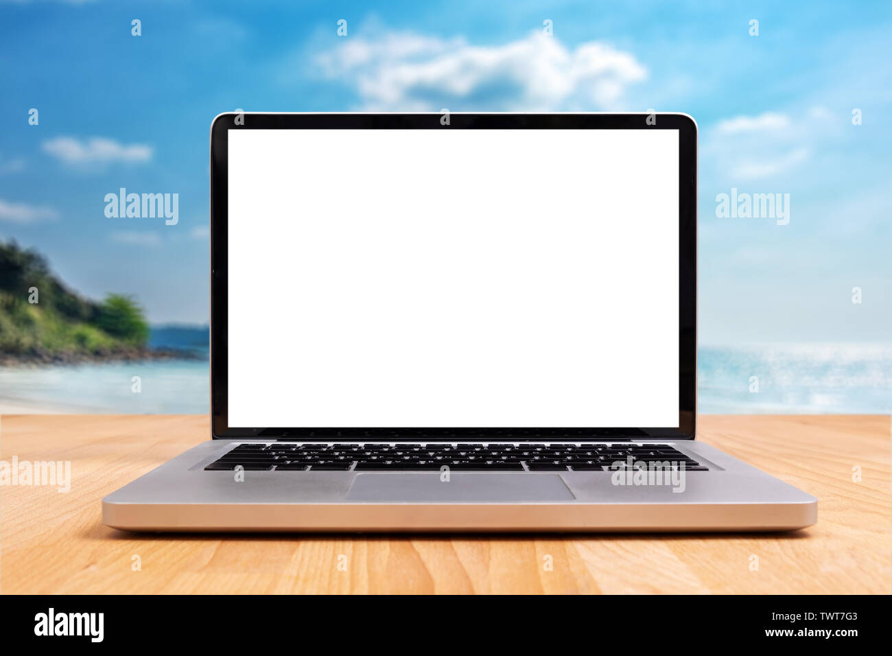 Laptop mit Leeren leeren weißen Bildschirm für Kopie Platz auf Schreibtisch aus Holz mit verschwommenen Sommer Meer Ocean Beach im Hintergrund Stockfoto