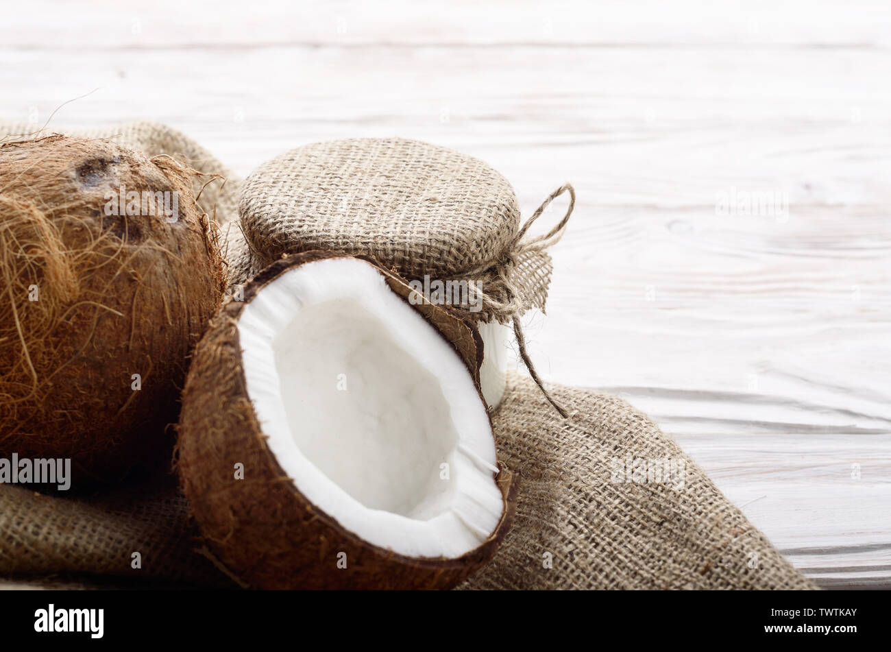 Coconut Shell mit Fleisch auf Hanf Sack auf weißen Küche aus Holz Tisch Stockfoto
