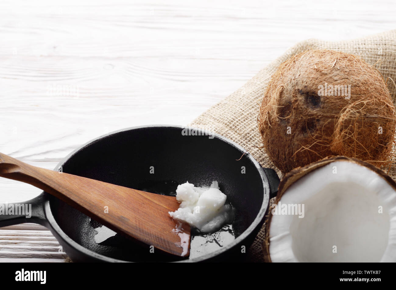 Kokosnuss, Shell mit Fleisch, Gusseisen Skillet und Spachtel auf Hanf Sack auf weißen Küche aus Holz Tisch Stockfoto