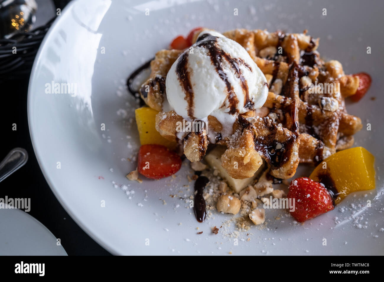 Waffeln mit Eis bedeckt Schokolade und mit Obst auf einem Teller auf den Tisch eingerichtet. Stockfoto