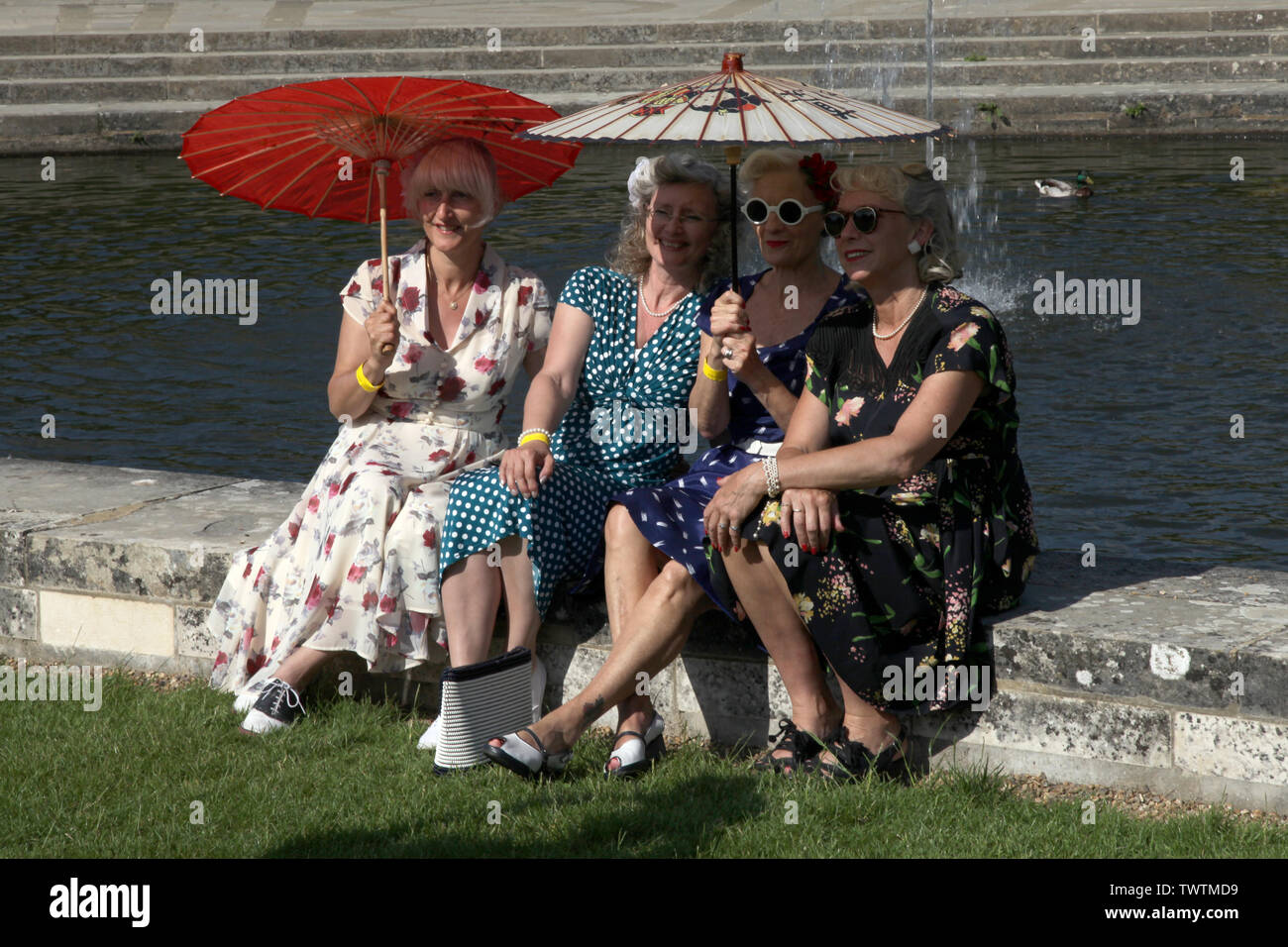 Edenbridge, Kent, UK - eine Gruppe der 1940er Jahre inspiriert Damen in Kriegszeiten Mode gekleidet Pose von einem Teich mit Sonnenschirmen Tag zu Hause Front Festival 2019 Stockfoto