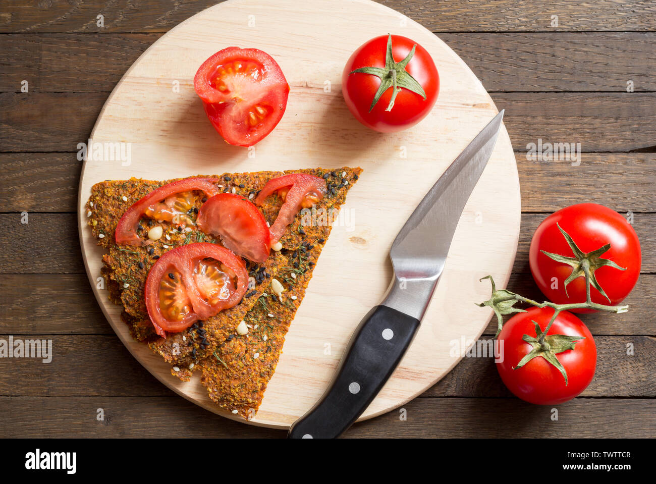 Rohkost Konzept. Dehydriert raw vegan trockenem Brot, geschnitten und ganze rote Kirschtomaten, Messer auf Küche Board auf Holztisch. Gesunde nutritio Stockfoto