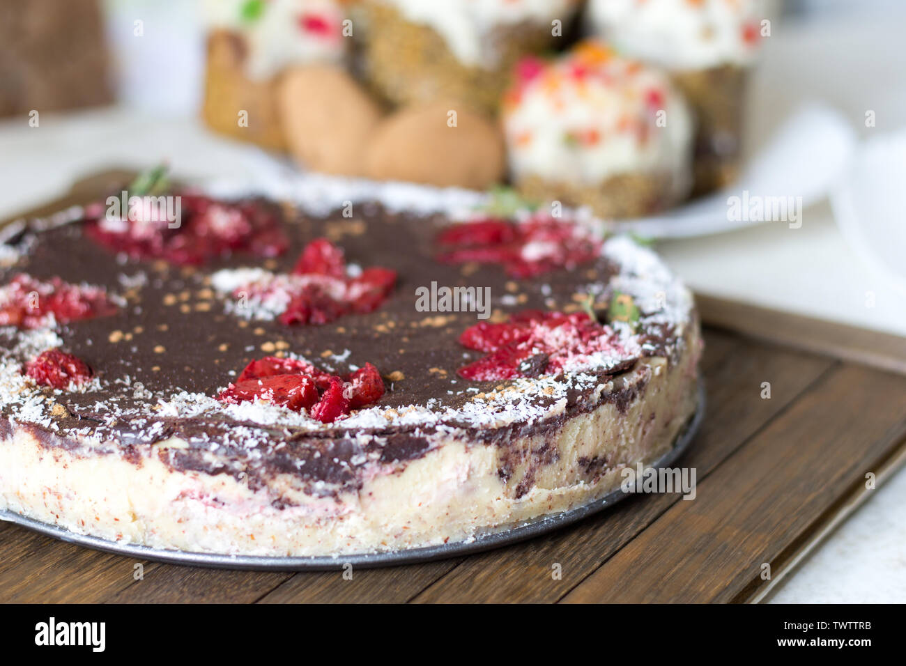 Gesunde Süßigkeiten Konzept. Сhocolate hausgemachte vegane Kuchen auf Holz Fach rohe Nahrungsmittel. Erdbeeren, natürliche Schokolade, bestreut mit carob Pulver und coconu Stockfoto