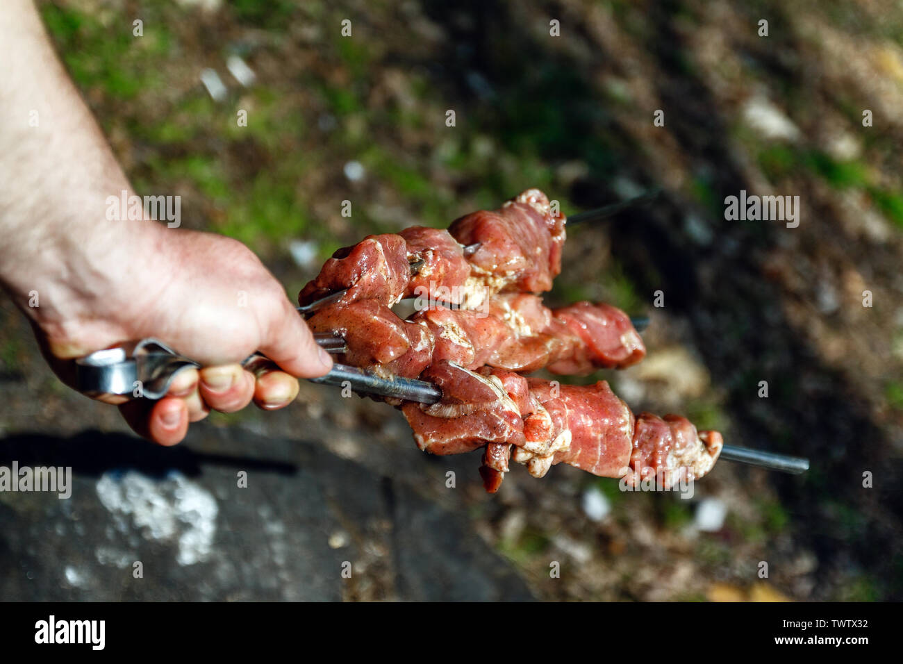 Mann hält in der Hand einen Spieß mit rohem Fleisch, Life Style. Stockfoto