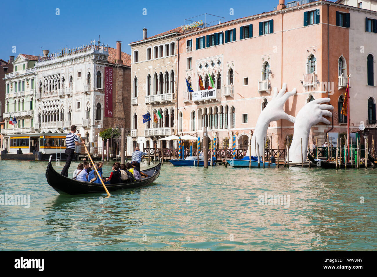 Venedig, Italien - April 2018: Touristen in einer gondel vor der Hände Skulptur des spanischen Künstlers Lorenzo Quinn im Venedig Canal Grande t erstellt Stockfoto