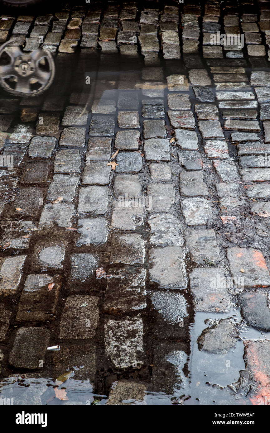 Grunge Straße mit Kopfsteinpflaster mit Pfützen, New York City Stockfoto