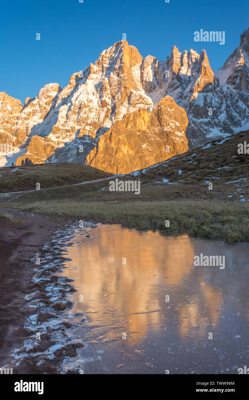 Goldene Berge auf dem Wasser auf einem zugefrorenen See in den italienischen Dolomiten wider. Mountain Range während der Goldenen Stunde, Wasser Reflexionen von Gipfeln. Stockfoto