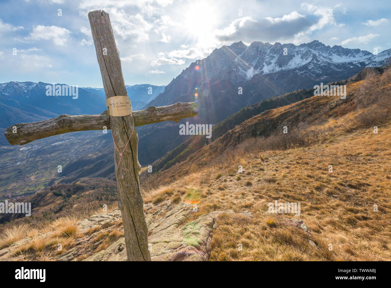 Direkte Sonneneinstrahlung, die Sonne scheint auf einen Berg Kreuz mit Rosenkranz auf einem Berg. Holzkreuz mit religiösen Zeichen auf der Bergspitze. Stockfoto