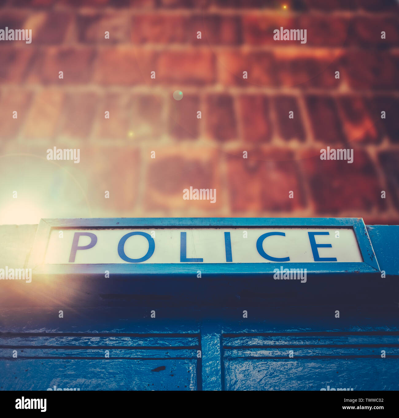 Britische Polizei Box mit Lens Flare gegen eine Red Brick Wall mit Kopie Raum Stockfoto