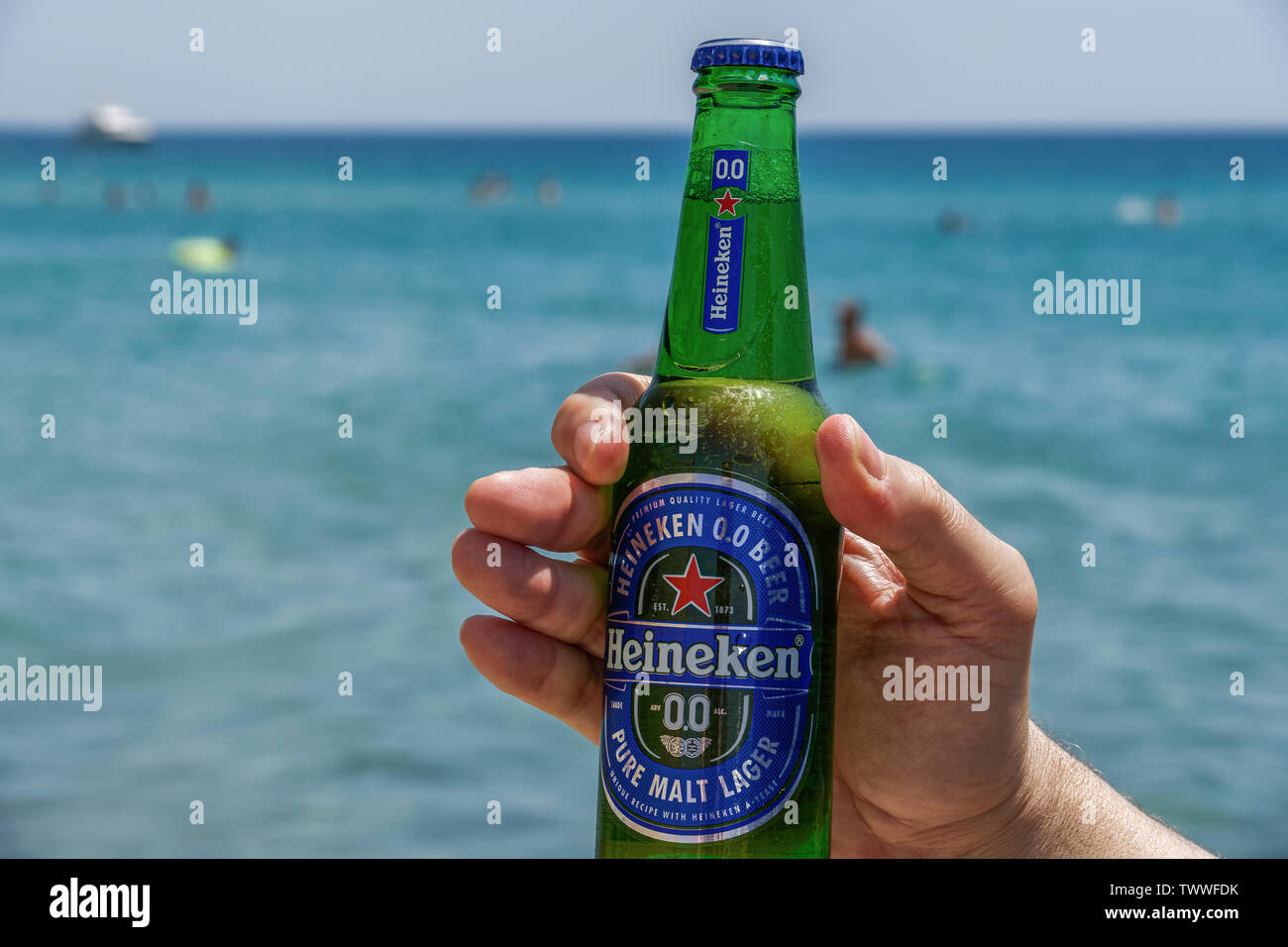 Hand holding Heineken null Alkohol Bier Flasche am Meer. Alkoholfreien Pilsener auf einem 33-cl-Glasflasche mit unscharfen Strand Meerblick Hintergrund. Stockfoto