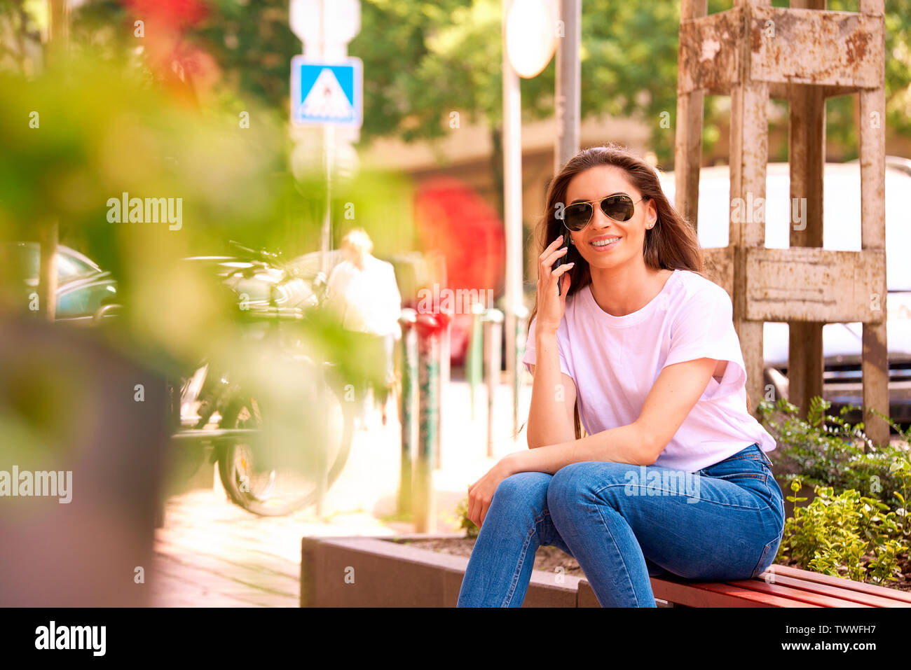 Portraitfotos der schöne junge Frau sitzt auf der Straße und Sie einen Anruf tätigen. Stockfoto