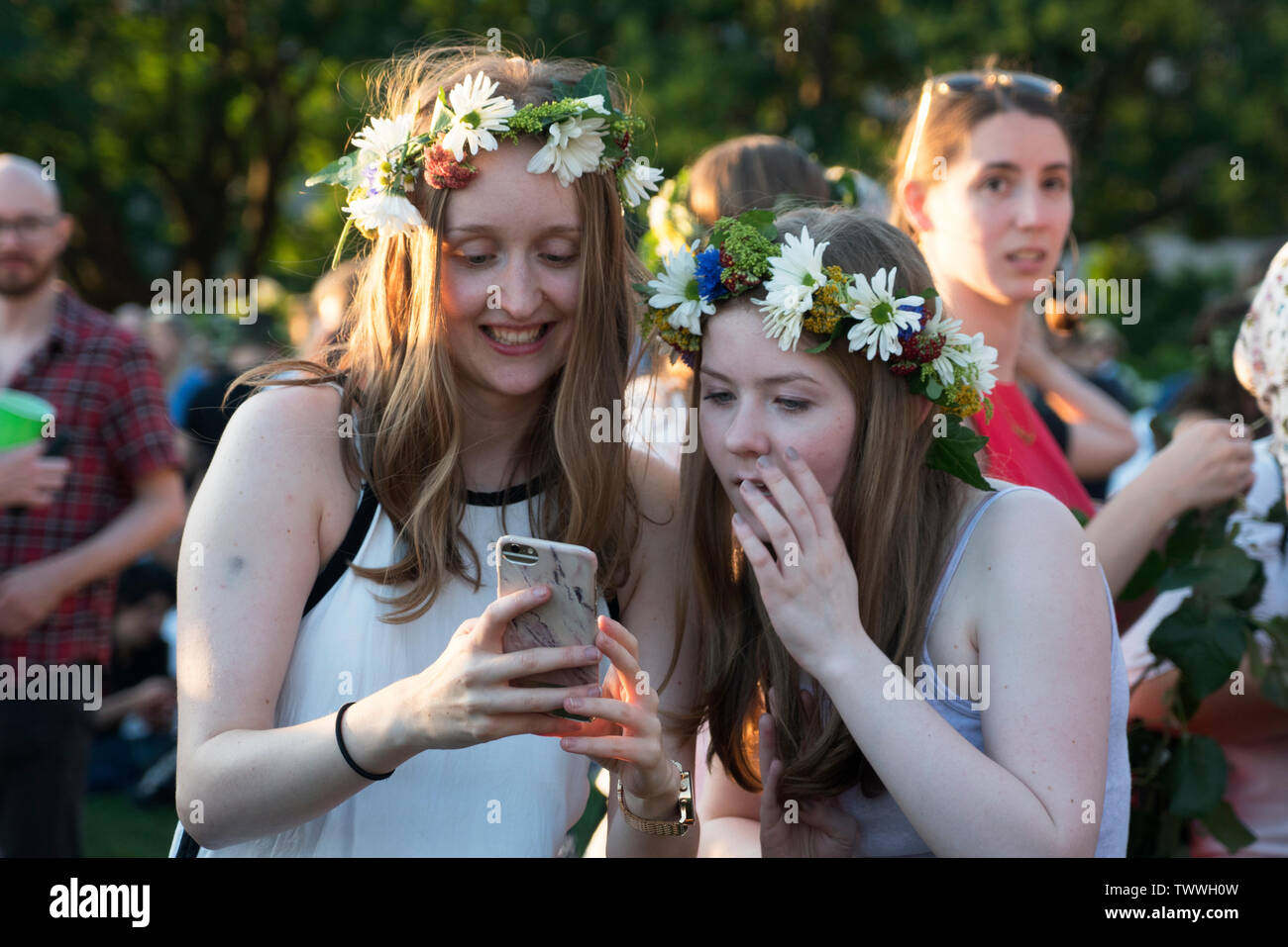 Zwei Frauen in ein Handy mit Unterhaltung und Erstaunen während der jährlichen Schwedischer Midsummer Festival in Battery Park City Wagner Park. Stockfoto