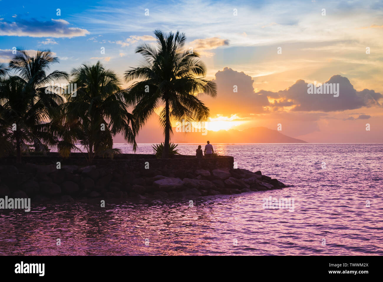 Silhouette von Palmen und romantische junge Paar den Sonnenuntergang genießen. Stockfoto