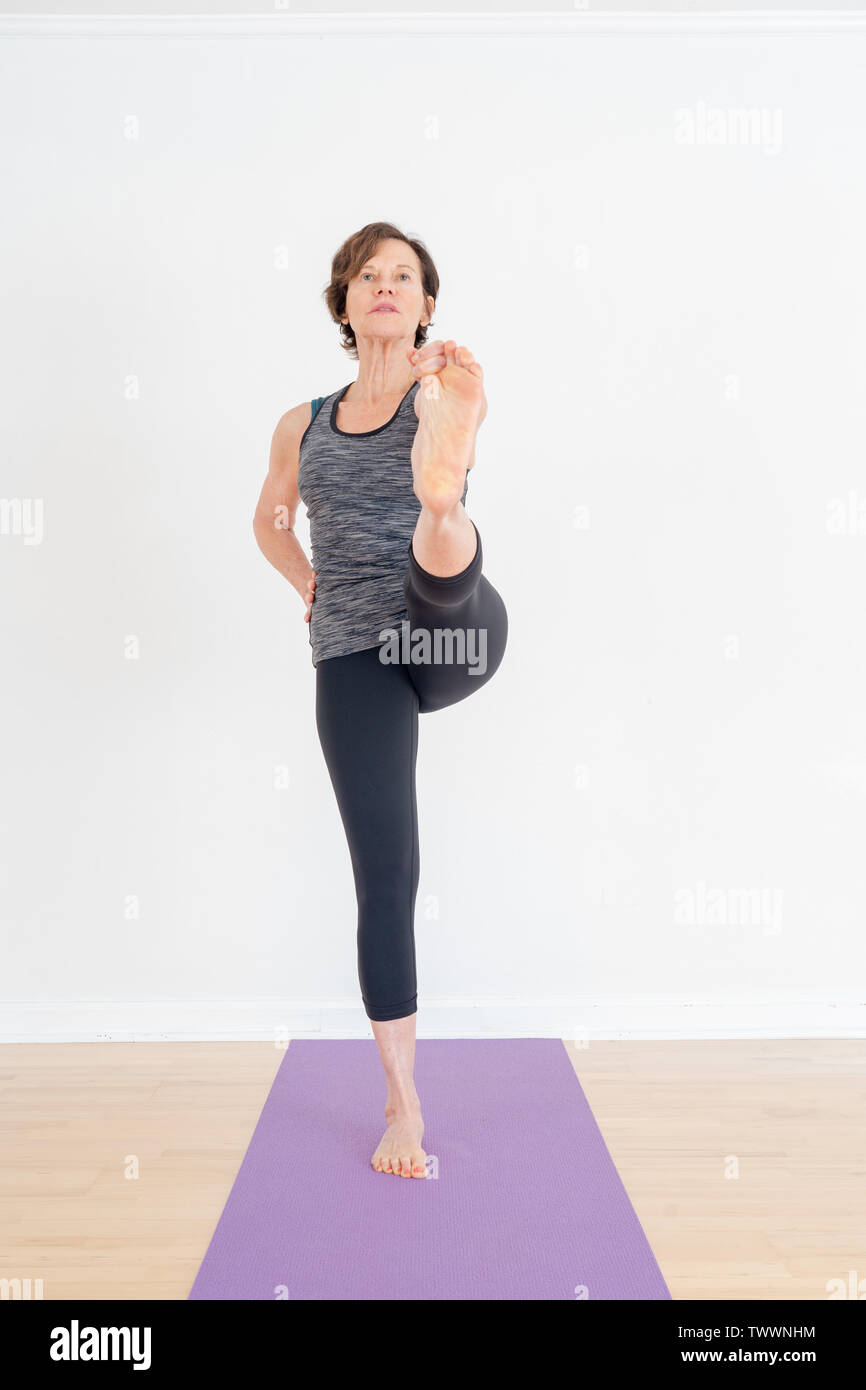 Eine 70 Jahre alte Yoga Lehrer in ihrem Atelier ist die verlängerte Hand-zu-Big-Toe darstellen Stockfoto