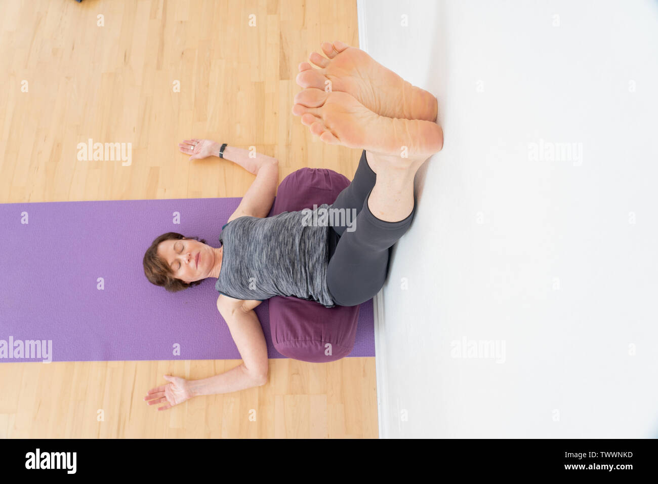 Eine 70-jährige Weiblich yoga Kursleiter verwendet stärkt in einer Restaurativen yoga Pose Stockfoto