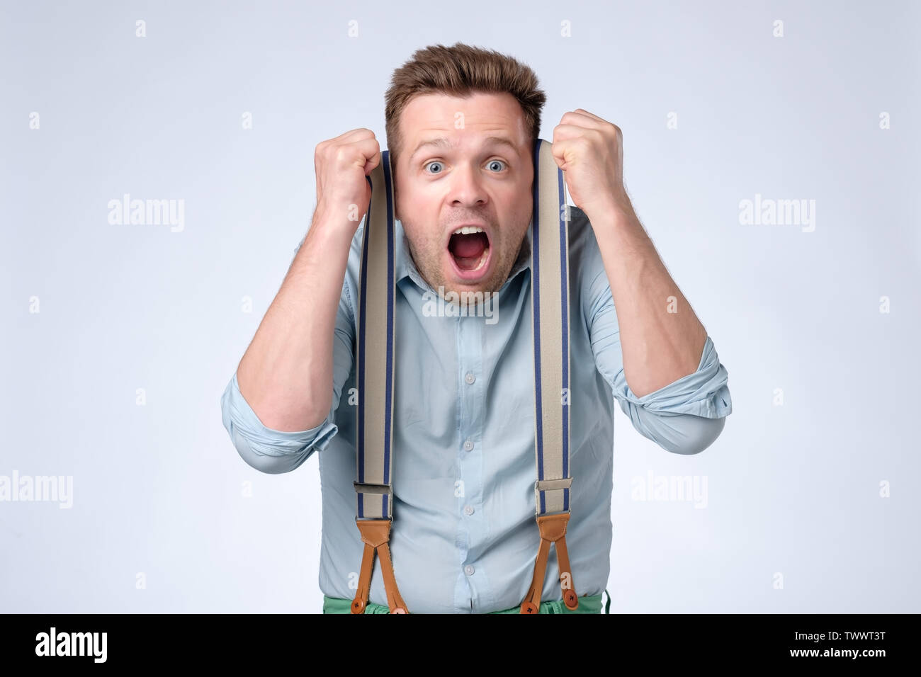 Gesicht der jungen europäischen Mann im blauen Hemd und Hosenträgern Schockiert Stockfoto