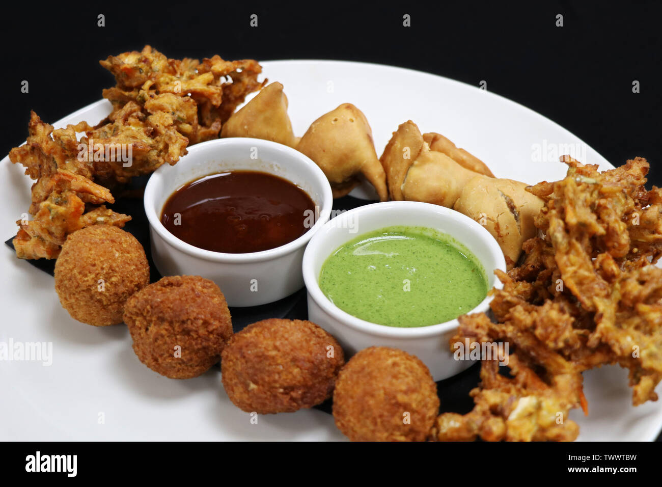 Verschiedene indische Snack pakora Platte mit paneer Kugeln, Zwiebel Chips und Punjabi Samosa Stockfoto