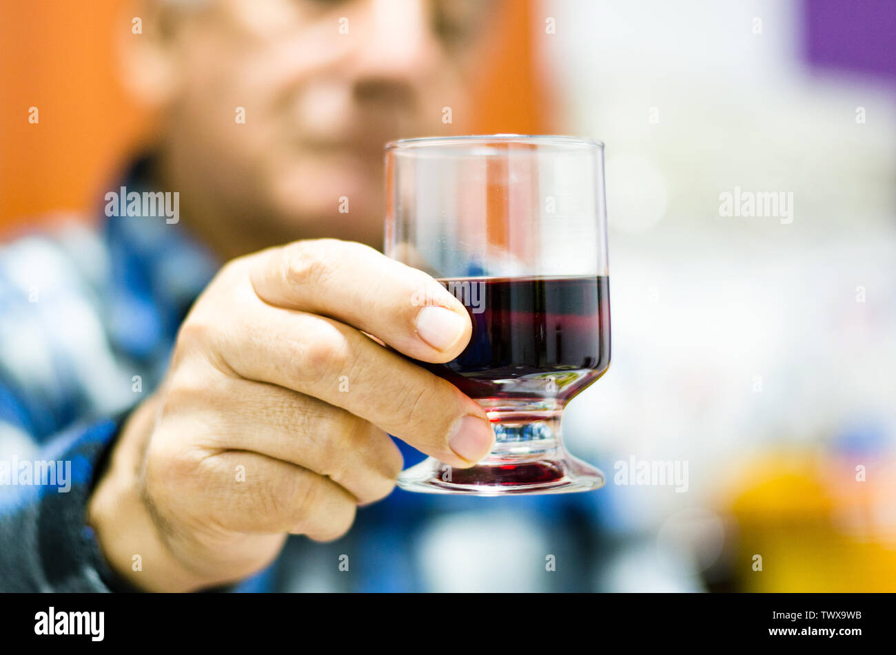 Mittleres alter Mann mit und Suchen in einem Glas Wein. Stockfoto