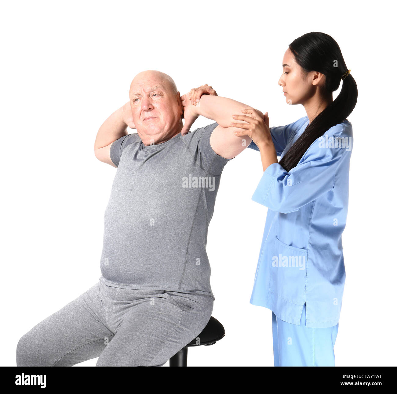 Jungen asiatischen Physiotherapeuten arbeiten mit älteren Menschen auf weißem Hintergrund Stockfoto