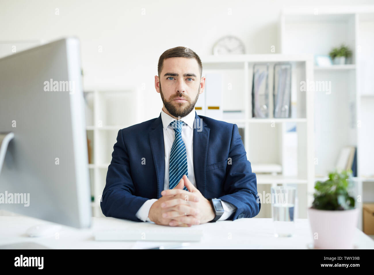 Porträt von Ernst zuversichtlich hübscher junger Bartgeier Business Executive am Tisch sitzen mit Computer im Büro Stockfoto