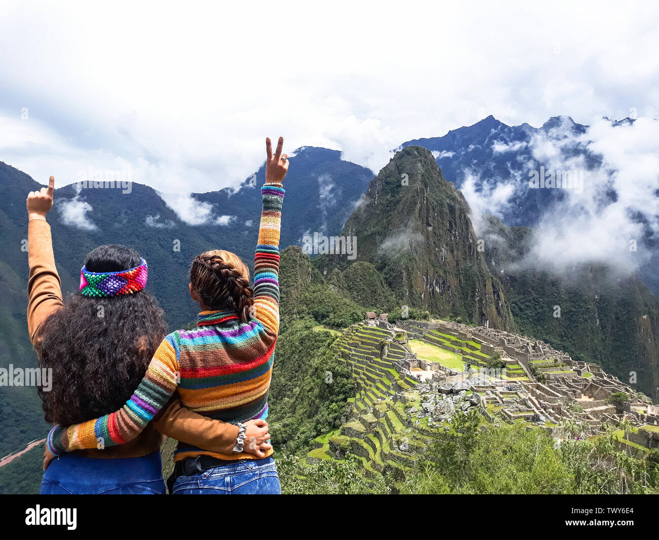 Junge Frauen mit Waffen in den Hintergrund von Machu Picchu angehoben. Alte Inkastadt, Peru Stockfoto